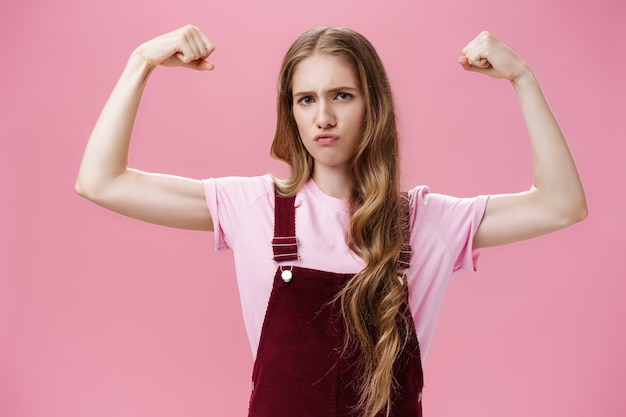 Girl shows she strong and independent seriouslooking confident slender female raising hands to show ...