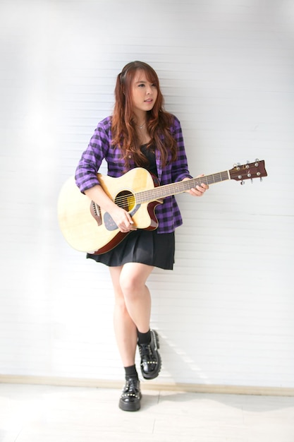 Girl singing on microphone and playing guitar