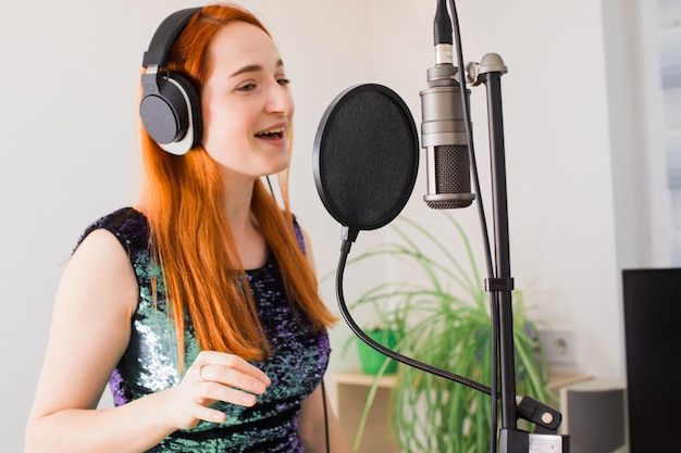 Photo the girl sings at home using professional equipment