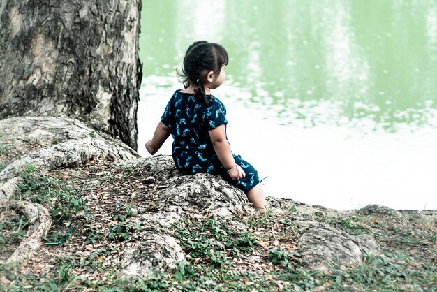 女の子は湖のそばに座る