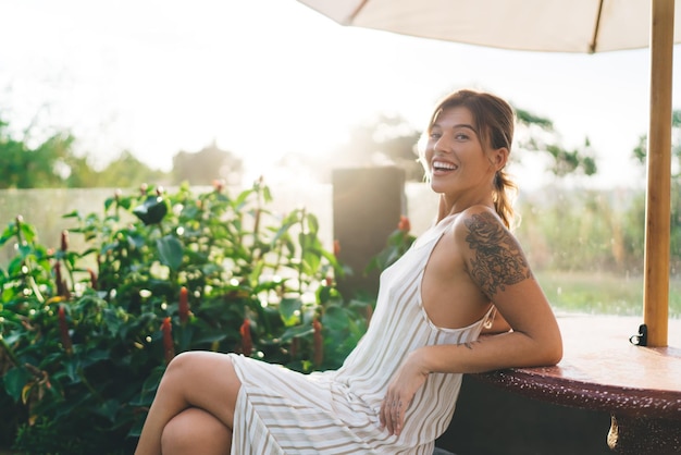 Photo girl sit and rest at table in yard of resort hotel