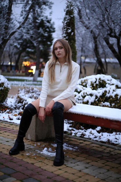 a girl sits on a bench in the snow