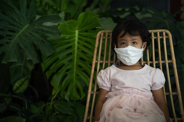 A girl sits in a chair wearing a mask.