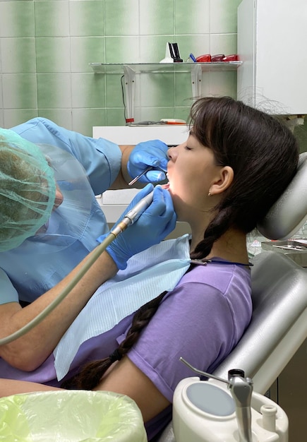 Girl sits in a dentist's chair, at a doctor's appointment, which she conducts an ultrasonic cleaning