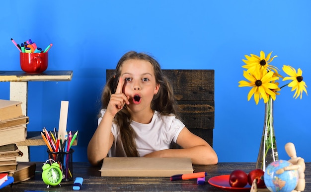 Girl sits at desk with school supplies