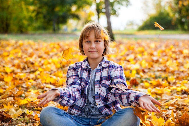 A girl sits on a field with yellow leaves