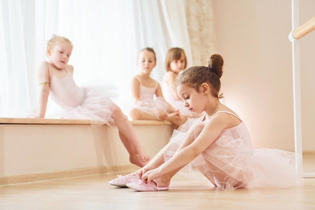 Photo girl sits on the floor little ballerinas preparing for performance by practicing dance moves