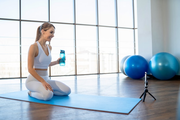 Girl sits in front of phone camera and records online workout