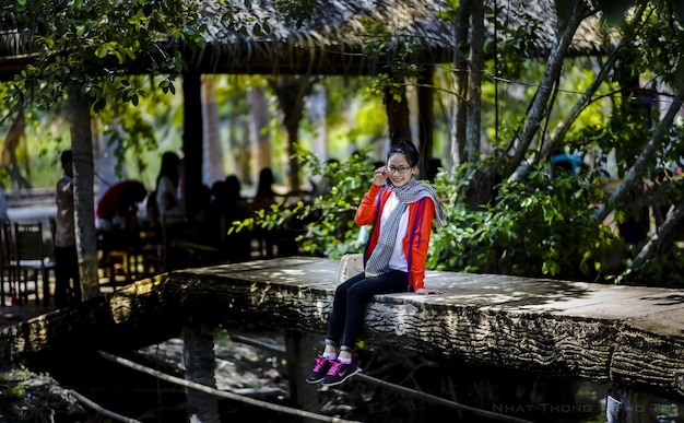 Photo a girl sits on a log in a forest.