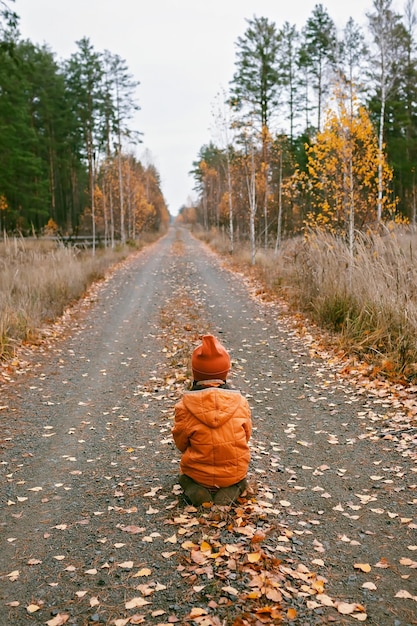 Девушка сидит и с нетерпением ждет дороги в осеннем лесу, думая о психическом здоровье осенних флюидов