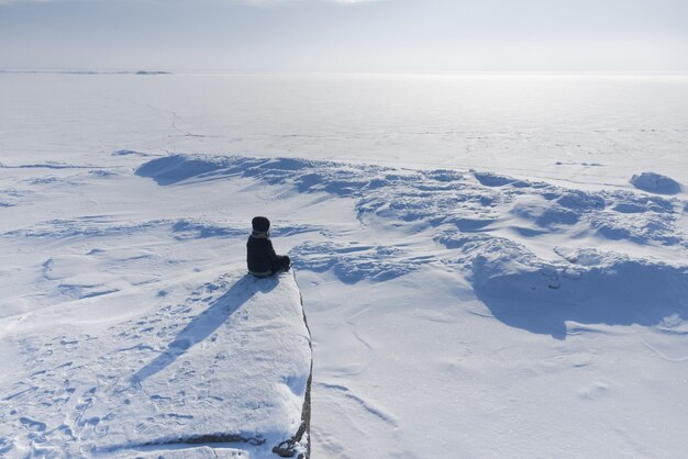 Photo a girl sits on the shore of a frozen sea and looks into the horizon