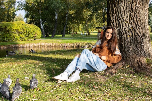 A girl sits on the shore of a pond