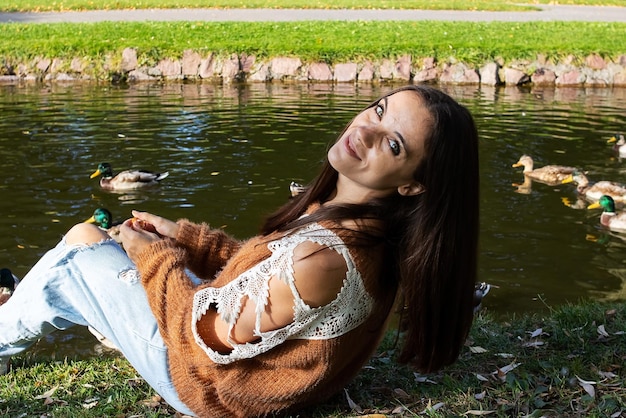 A girl sits on the shore of a pond