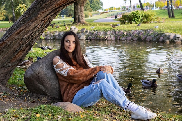 A girl sits on the shore of a pond