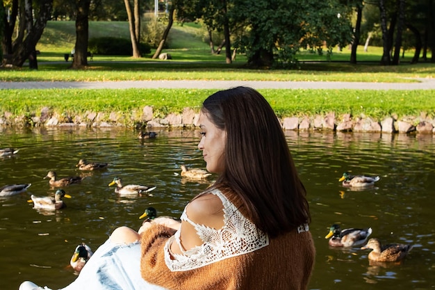 A girl sits on the shore of a pond