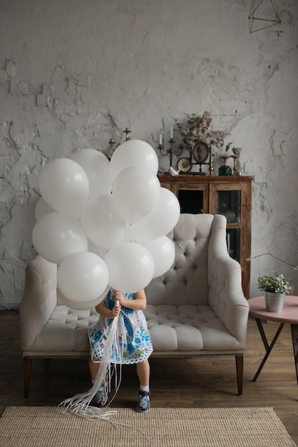 The girl sits on the sofa and holds white balls in her hands