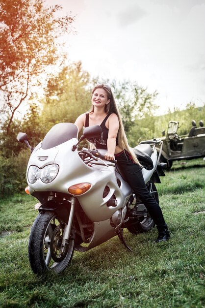 Girl sits on  sports bike on the background of lake