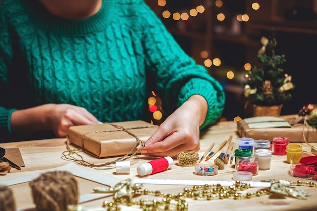 Photo girl sits at the table wraps christmas presents