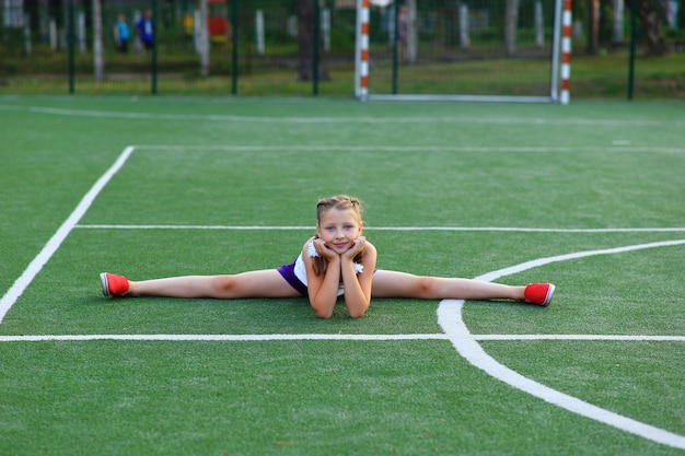 Photo the girl sits on the twine on the sports ground.