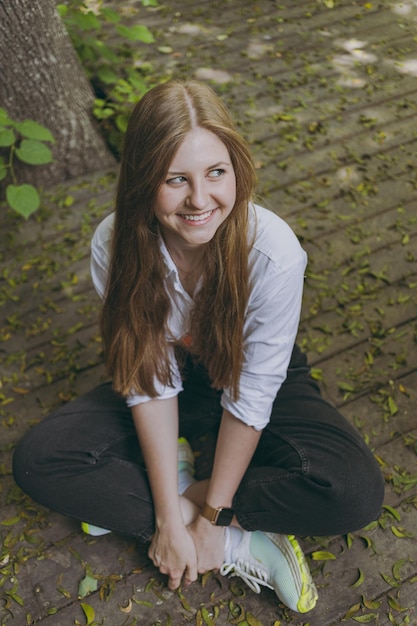 The girl sits on the wooden floor and laughs