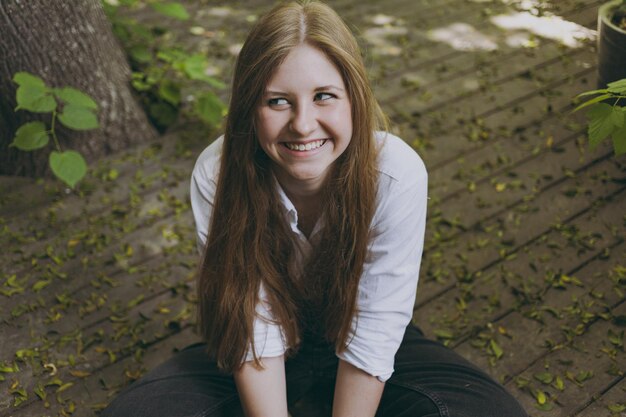 A girl sits on the wooden floor and laughs