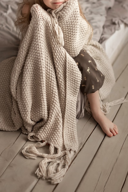 girl sitting on the bed in the bedroom wrapped in a blank