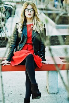 Ragazza seduta sulla panchina. moda di strada. stile di vita urbano. giovane bella donna che cammina all'aperto. immagine dai toni.