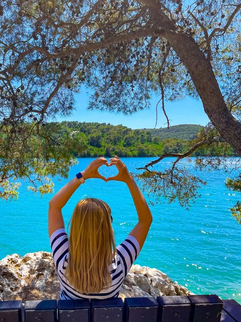 A girl sitting on a bench with her back on the shore of the mljet national park in croatia