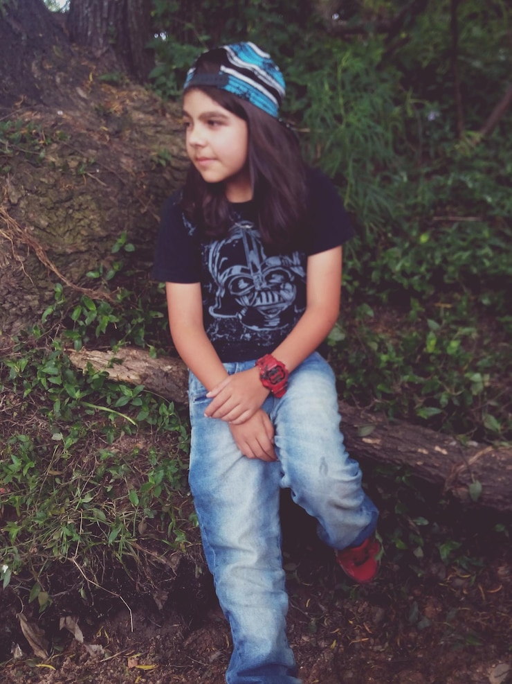 Photo girl sitting on branch by plants