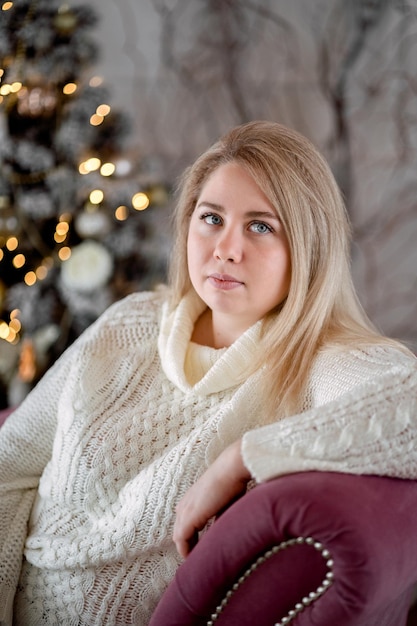 Ragazza seduta vicino all'albero di natale