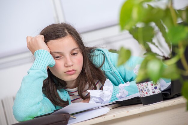 写真 テーブルの上にくっついた紙のそばに座っている女の子