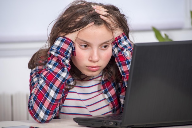 Girl sitting by laptop on table