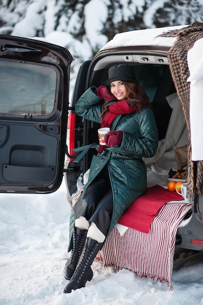 A girl sitting in a car in a winter forest Outdoor recreation Demonstration of clothes