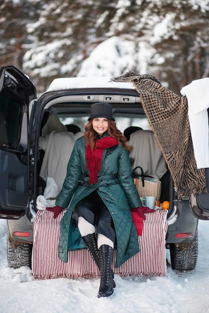 A girl sitting in a car in a winter forest Outdoor recreation Demonstration of clothes