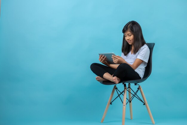 Photo girl sitting on a chair watching tablet