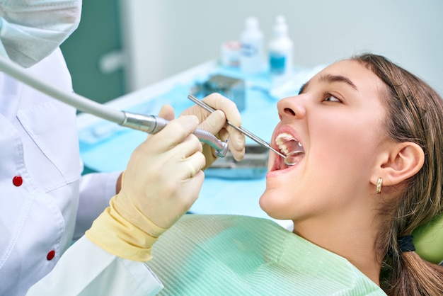 Girl sitting at dental chair with open mouth during oral check up while doctor. Visiting dentist office. Dentistry concept