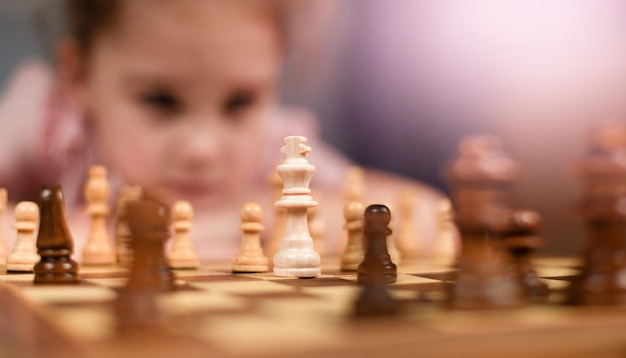 Photo a girl sitting in front of a chessboard and pondering a move