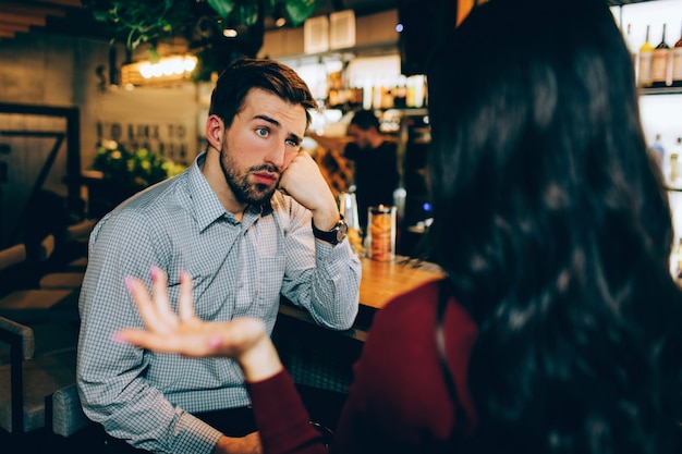 Girl sitting in front of young guy and talking to him