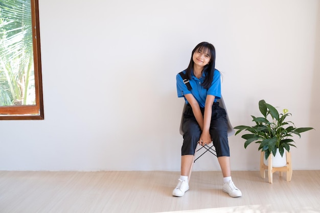 The girl sitting on the gray chair with green plant in minimal room