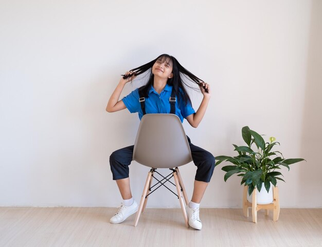 最小限の部屋で緑の植物と灰色の椅子に座っている女の子