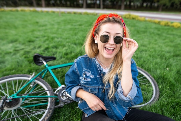 自転車の近くの公園の緑の芝生に座っている女の子