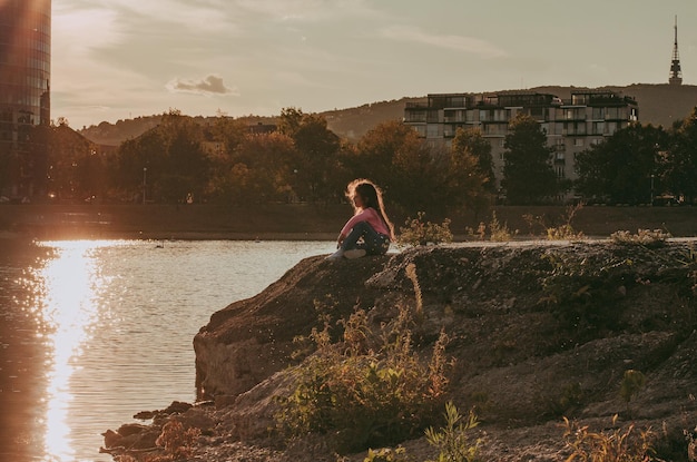 Foto ragazza seduta sulla terra contro il cielo durante il tramonto