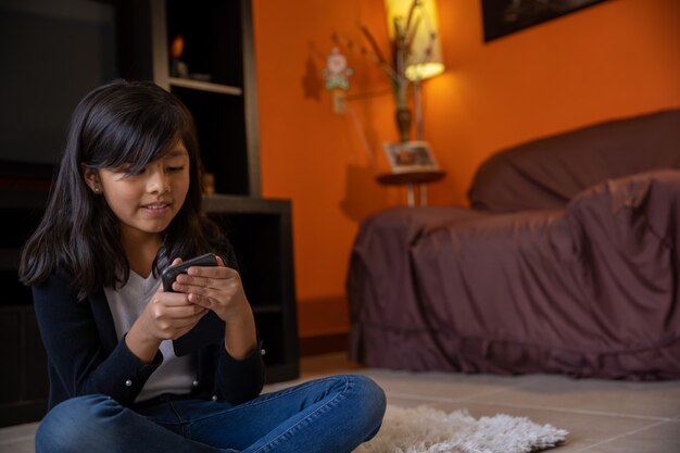 Girl sitting on a mat with the cell phone at home video conference