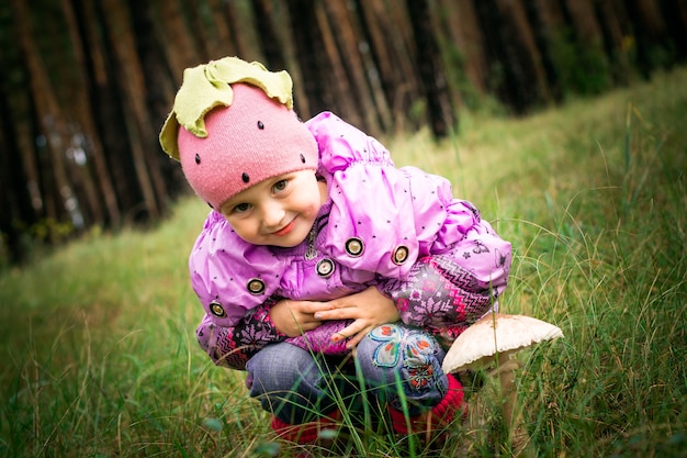 Photo girl sitting next to a mushroom toadstool girl on a background of forest