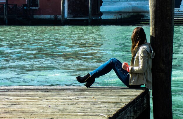 Girl sitting near the river on pier