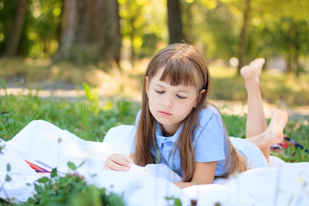사진 카펫에 앉아 색연필로 그림을 그리는 소녀는 학교 밖에서 즐거운 시간을 보내기 위해 배우고 있습니다.