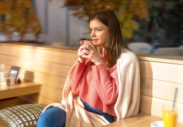 Девушка сидит за пределами кафе на открытом воздухе солнечный осенний день Кофе-брейк