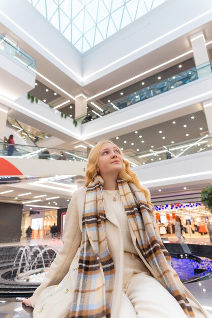 Girl sitting on the parapet at the mall near the fountain