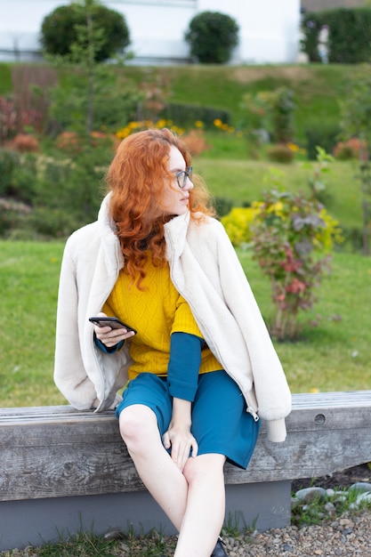 Girl sitting in a park with cellphone