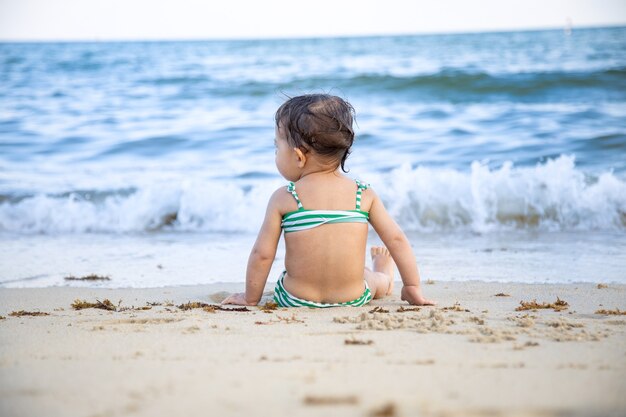 Ragazza seduta sulla spiaggia di sabbia.